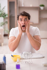 Young man shaving face at home