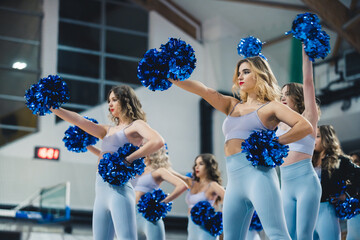 Medoim shot of a cheerleading group in matching outfits doing a choreography. Sport concept. High...