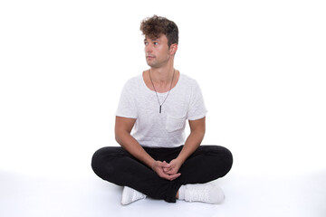 man look shocked and astonished to side while sit with crossed legs isolated on floor