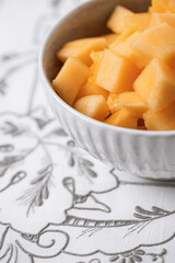Close Up of a Bowl of Cantaloupe on Gray and White Tablecloth