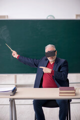 Old male teacher wearing virtual glasses in the classroom