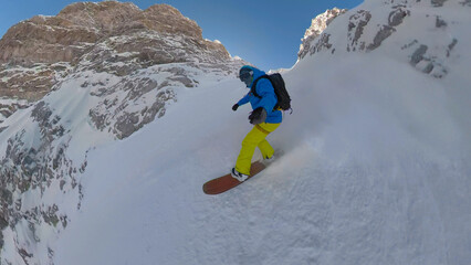 PORTRAIT, SELFIE: Male snowboarder riding down the couloir in fresh powder snow