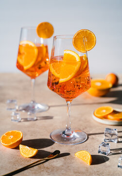 Close up of two aperol spritz drinks on sunny beige background.