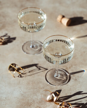 Close up of two glasses of champagne on sunny beige background.