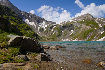 Gebirgssee in den Alpen mit blauen Himmel und weißen Wolken