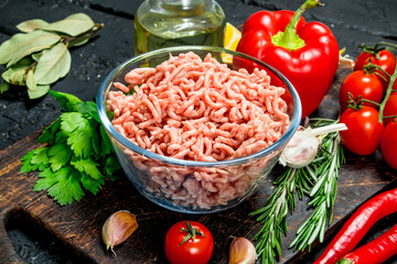Raw minced meat in a bowl with vegetables and herbs.