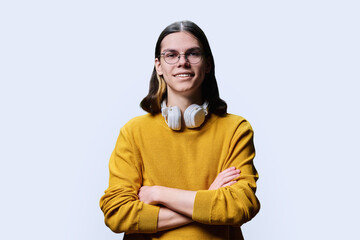 Confident young male posing with crossed arms against light background