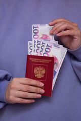 Vertical photo. Russian biometric passport. 100 GEL. Woman holds Georgian paper banknote and...