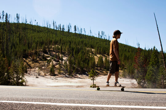 A young man longboarding in a national park in Montana.