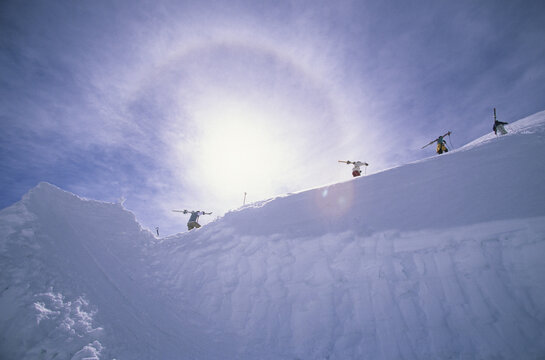 Four skiers hiking to hit a jump.
