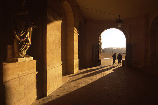 Two men walking through archway at the Palace of Versailles, France.