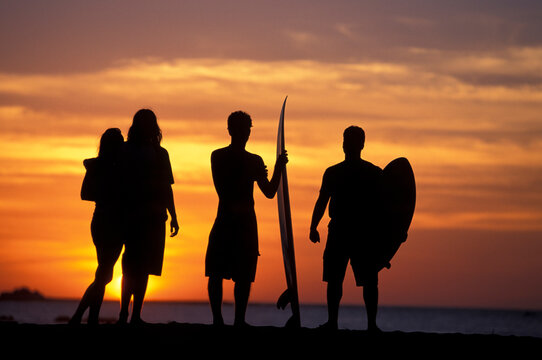 Friends hanging out on the beach at sunset.