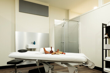 Massage table with interchangeable paper roller and wood therapy parts in a beauty salon cabin