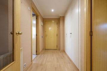 Entrance hall with armored door of an empty house with white built-in cabinets and light wooden doors