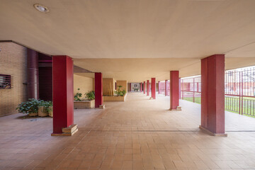 Common areas of a residential building with red painted pillars and small clay tile floors