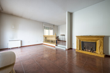 Living room of a single-family home with a double-height living room, wooden railing and fireplace with brown marble