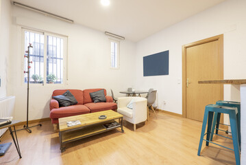 Loft-style apartment with a pine wood bar counter with blue metal stools and a two-seater armchair with an industrial design coffee table