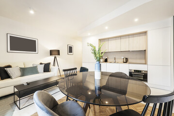 Loft apartment with glass round black dining table with vase and contemporary designed open plan kitchen