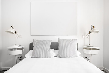 Detail of a bedroom with metallic design bedside tables with matching windows and a gray headboard with striped cushions