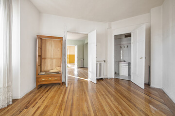 Empty house with some loose wooden furniture, such as a closet without a door, access to a bathroom, and wooden floors