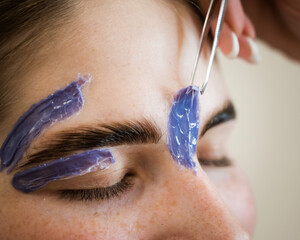 Eyebrow correction. The master removes excess hairs with wax and tweezers.