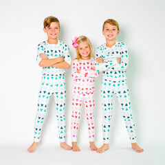 Holiday family pajamas portrait with three siblings shoulder to shoulder