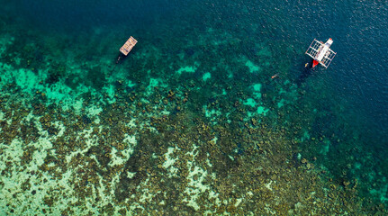 Naklejka na ściany i meble Catamaran Sailing Near Snorkeler In Shallow Coral Reef In The Ocean In Palawan, Philippines