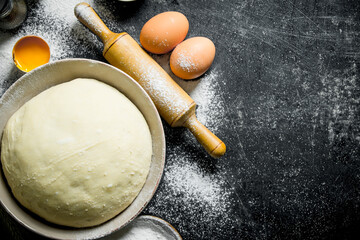 Dough with rolling pin and eggs.