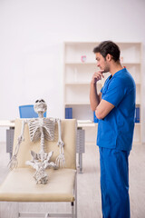 Fototapeta premium Young male doctor and skeleton patient in the clinic