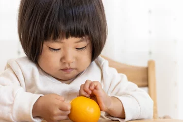 Foto auf Leinwand 座ってミカンを食べる赤ちゃん（2歳4か月、女の子、日本人） © poko42
