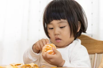 Foto auf Leinwand 座ってミカンを食べる赤ちゃん（2歳4か月、女の子、日本人） © poko42
