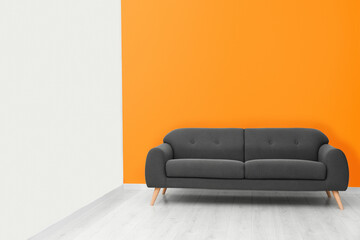 Stylish room with cosy sofa near orange wall, space for text. Interior design