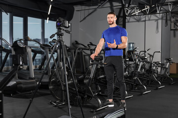 Fototapeta na wymiar Man recording online training on camera at gym. Fitness coach