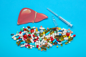 Paper liver, syringe, vial and pills on light blue background, flat lay. Hepatitis treatment