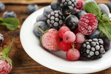 Mix of different frozen berries on wooden table, closeup