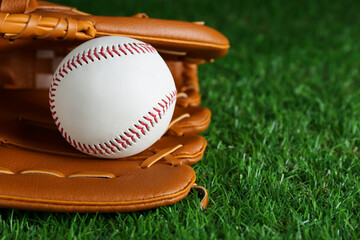 Catcher's mitt and baseball ball on green grass, closeup with space for text. Sports game