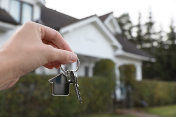 Woman holding house keys outdoors, closeup with space for text. Real estate agent