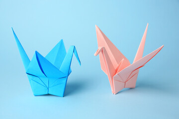 Fototapeta premium Origami art. Colorful handmade paper cranes on light blue background