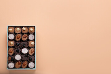 Box of delicious chocolate candies on beige background, top view. Space for text