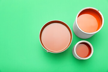 Cans of orange paint on green background, top view. Space for text