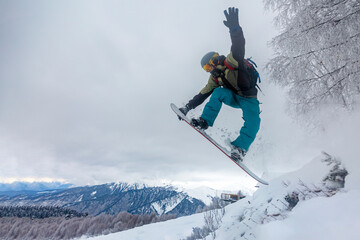 incredible snowboard jump under the white snowy forest on a good winter day, freeride in deep snow, ski season