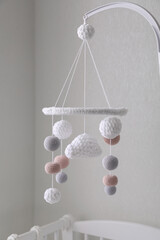 Modern baby crib mobile near beige wall in room