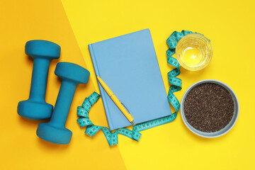 Weight loss concept. Flat lay composition with notebook, measuring tape and glass of water on color...