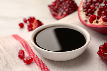 Bowl of pomegranate sauce and fresh ripe fruit on table, closeup