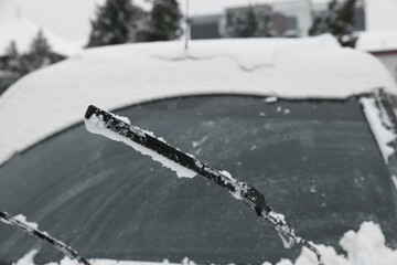 Car windshield with wiper blades cleaned from snow outdoors on winter day
