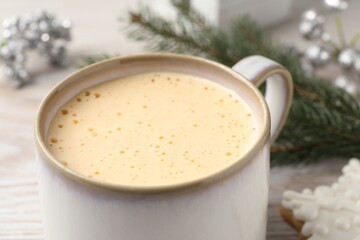 Cup of delicious eggnog on table, closeup