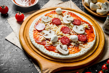 Preparation pizza. Rolled out dough with tomato paste, sausages, mushrooms and cheese.