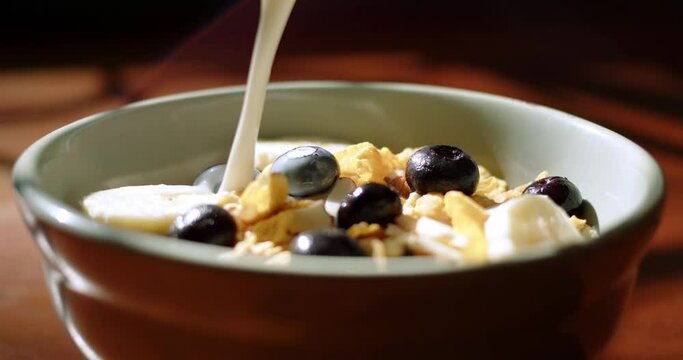 Tracking Close-up milk poured over cereal with berries and nuts.  4K ProRes 422 HQ DCI 4096 x 2160. Shot on the Blackmagic Cinema Camera 6K Pro on a slider, with rack focus and natural morning light. 