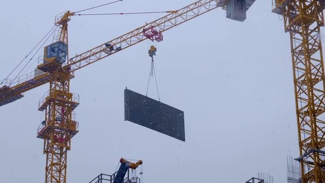 Construction site, where a modern beautiful multi-storey building is being erected by casting a monolith into a formwork reinforced with metal reinforcement. The crane carries the necessary constructi