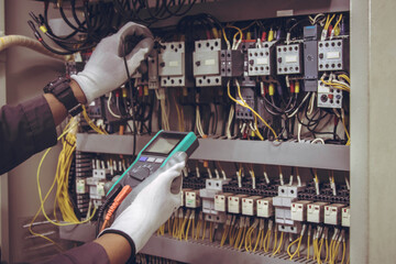 Electrician engineer tests electrical installations and wires on relay protection system.